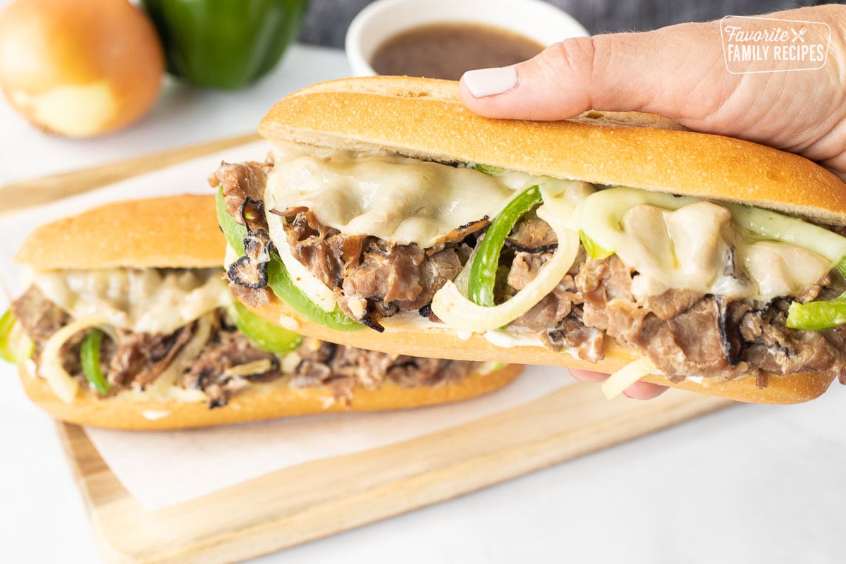 Hand holding a full Philly Cheesesteak.