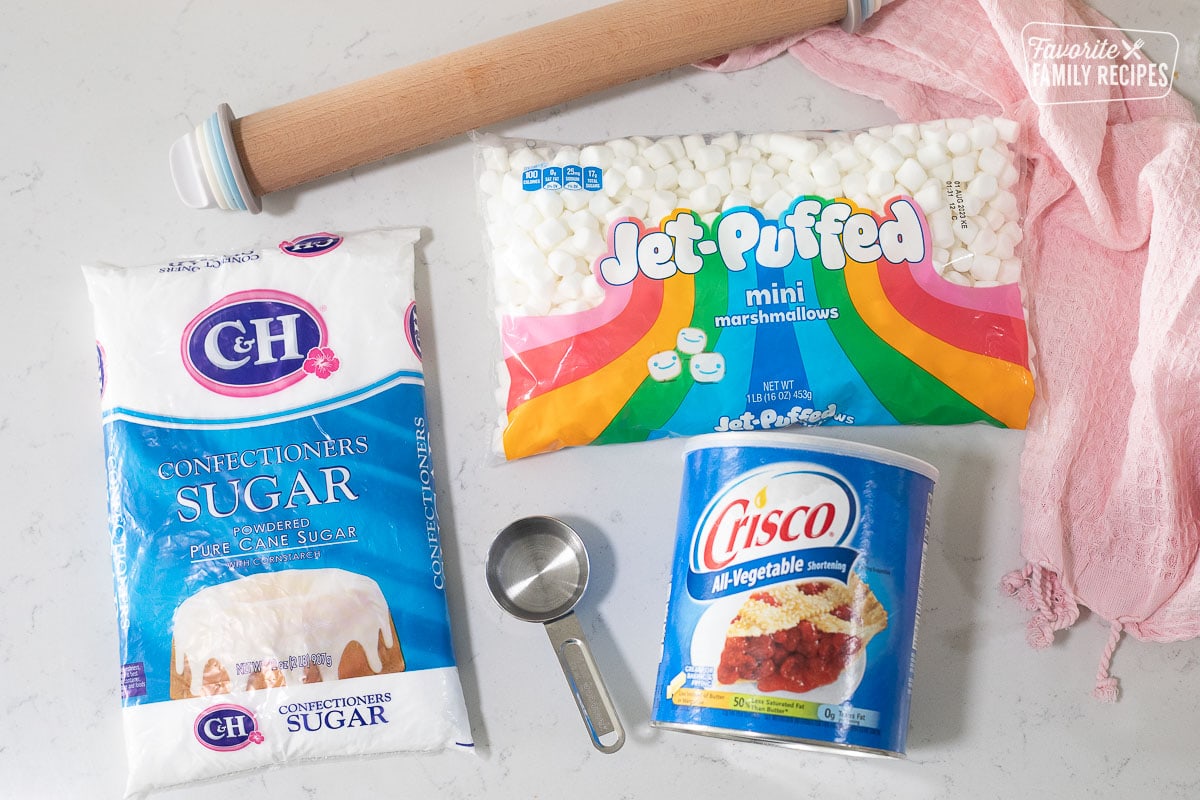 Ingredients showing how to make Fondant including powdered sugar, mini marshmallows, Crisco, water and rolling pin.