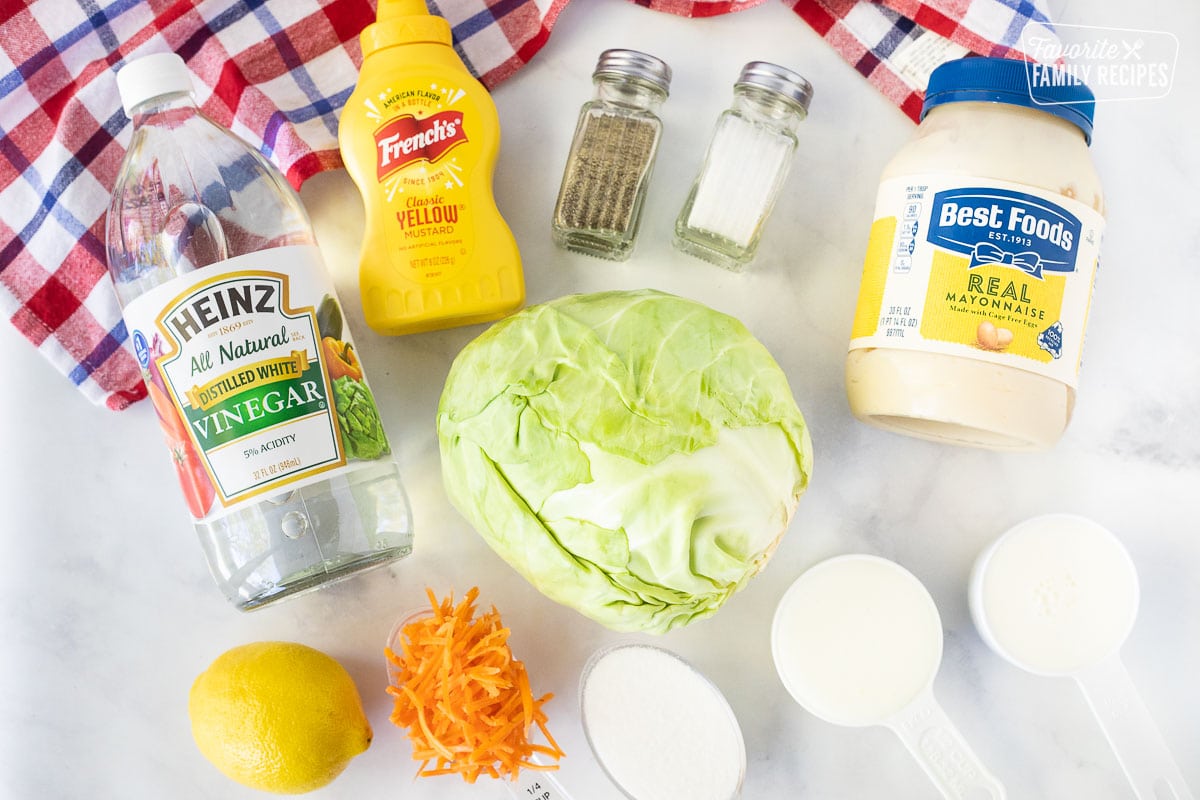 Ingredients to make Coleslaw including vinegar, yellow mustard, salt, pepper, mayonnaise, cabbage, carrots, lemon, buttermilk, sugar and milk.