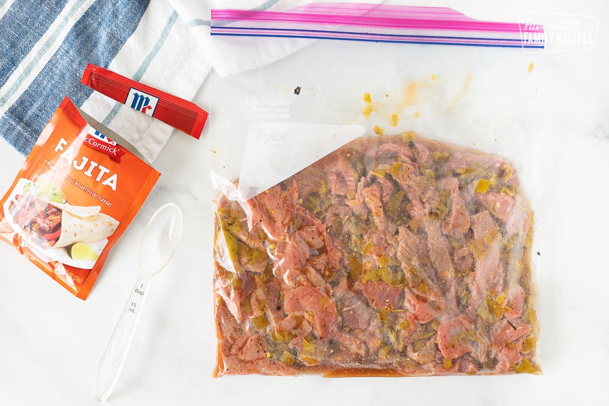 Ziplock back with sliced steak marinating with seasonings for Steak Fajita Bowls.