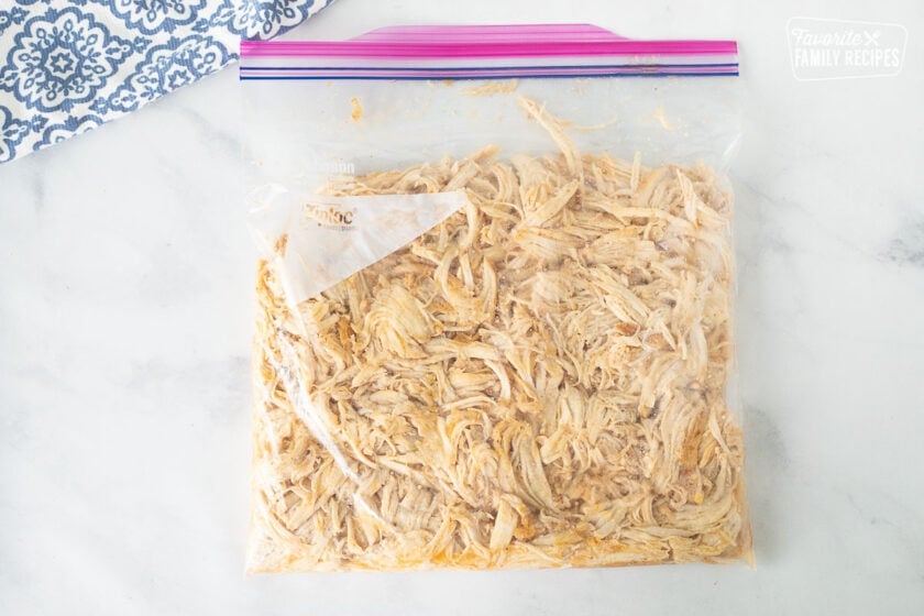 Ziplock bag with marinating shredded chicken for Honey Lime Chicken Enchiladas.