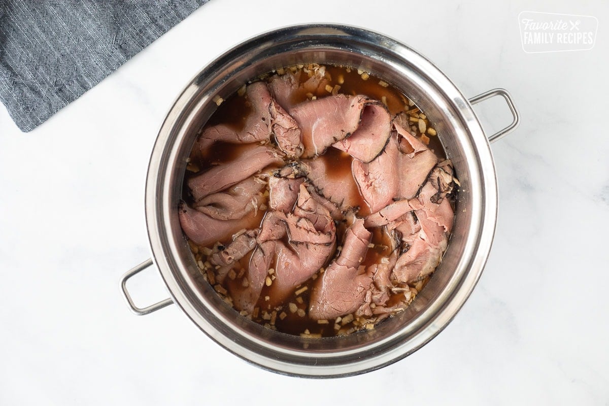 Pan of roast beef and broth base for Philly Cheesesteak.