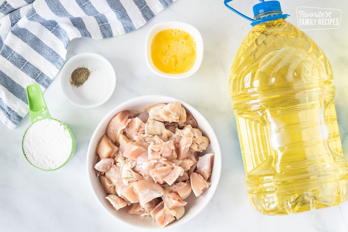 Ingredients to make Orange Chicken including cut chicken thighs, oil, egg, salt, pepper and corn starch.