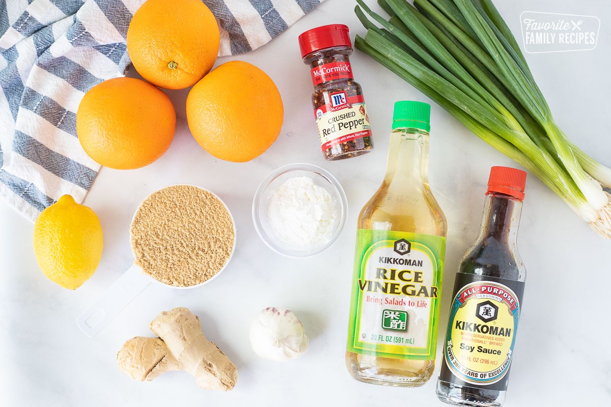 Ingrendients to make Orange Chicken sauce including oranges, lemon for juice, onions, red pepper, brown sugar, corn starch, ginger, garlic, rice vinegar, soy sauce and green onions.