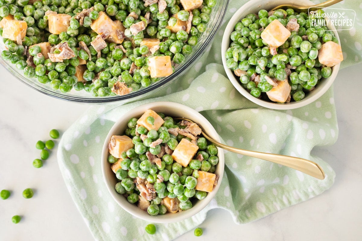 Top view of Green Pea Salad in small bowls next to large glass bowl.