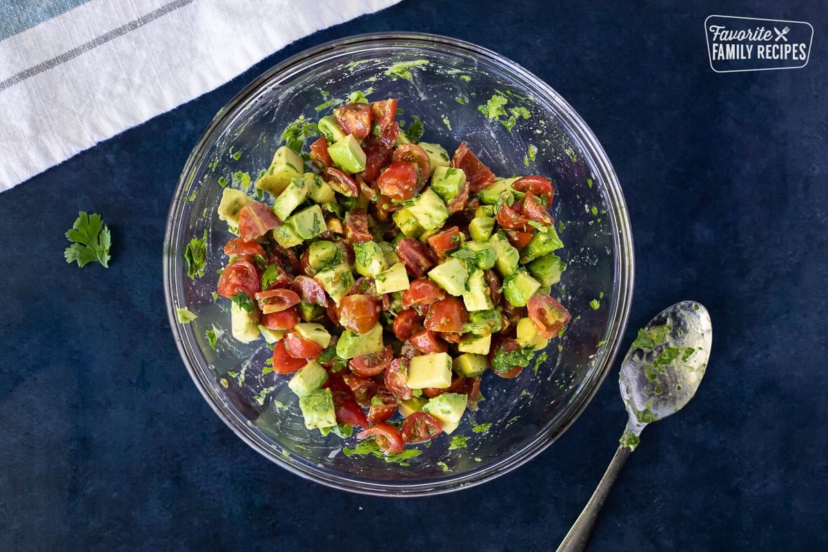 Pico de Gallo in a glass bowl with a spoon on the side.