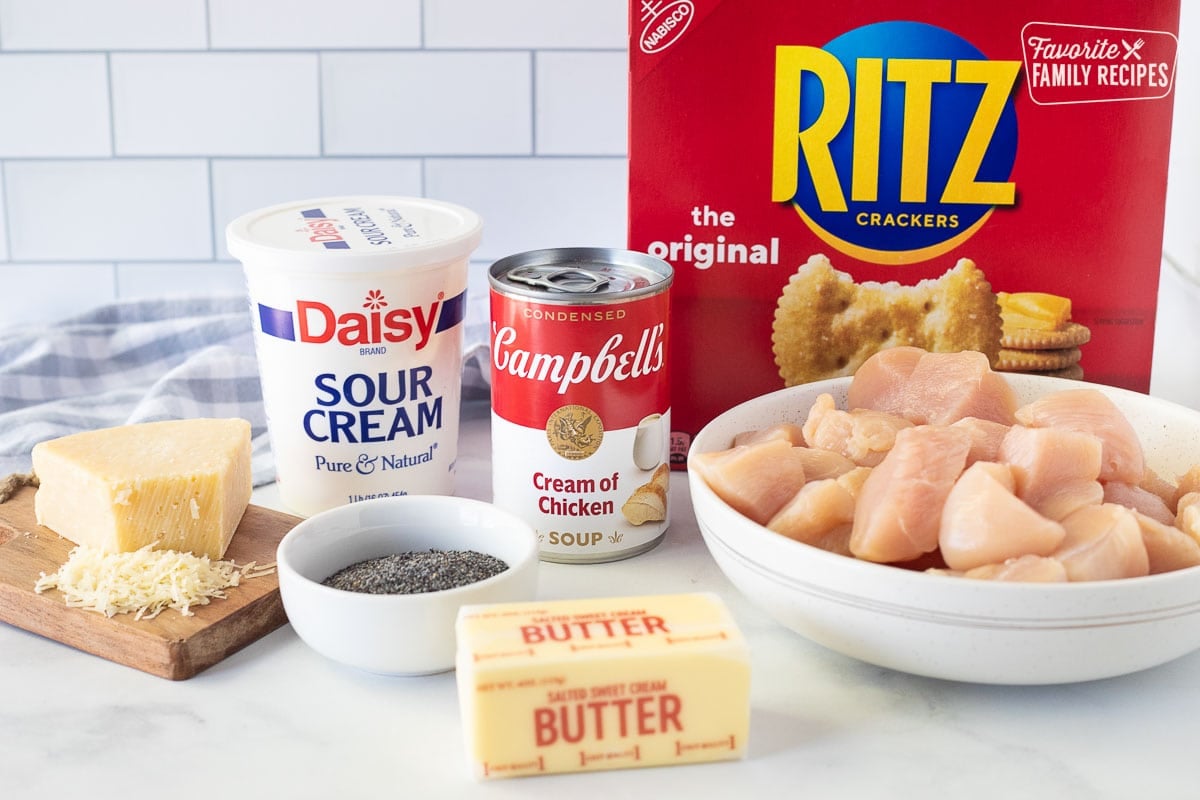 Ingredients to make Poppy Seed Chicken including Ritz crackers, cream of chicken soup, chicken, butter, sour cream, poppy seeds and grated parmesan cheese.