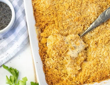 Spoon scooping in a baking dish of Poppy Seed Chicken.