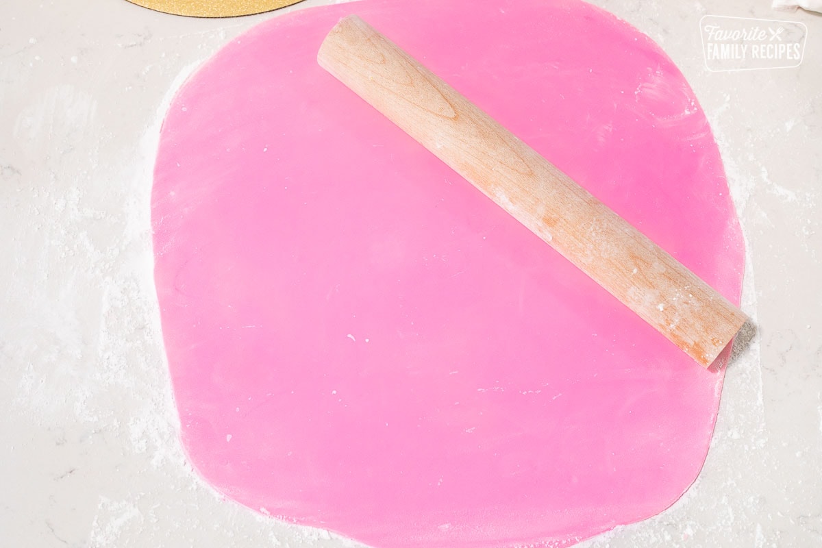 Rolled out pink fondant with rolling pin for Barbie Cake.