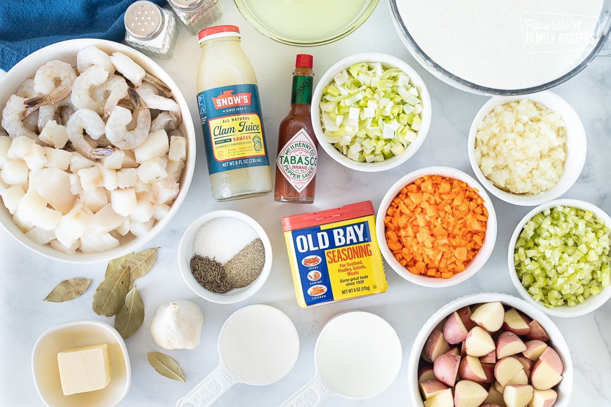 Ingredients to make Seafood Chowder including half and half, broth, clam juice, shrimp, cod, tabasco, old bay, onion, scallions, celery, carrots, red potatoes, flour, milk, spices, bay leaves, garlic and butter.