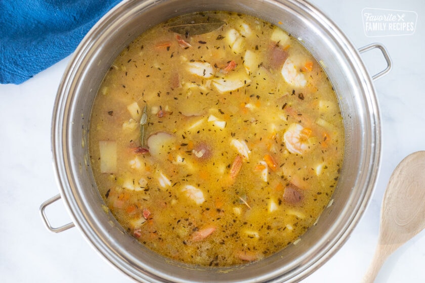 Cooked seafood in pot with vegetables and broth for Seafood Chowder.