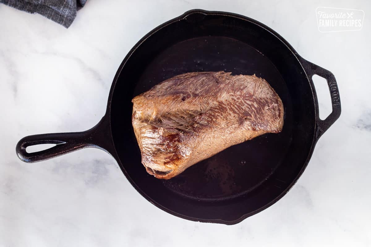 Skillet of beef roast with seared edges for Crockpot Roast Beef.