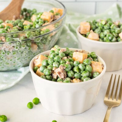 Serving bowls full of Green Pea Salad with forks.