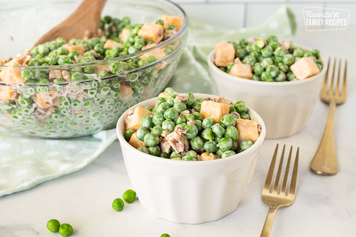 Serving bowls full of Green Pea Salad with forks.