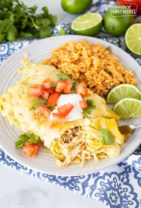 Fork holding a bite of Honey Lime Chicken Enchiladas on a plate.