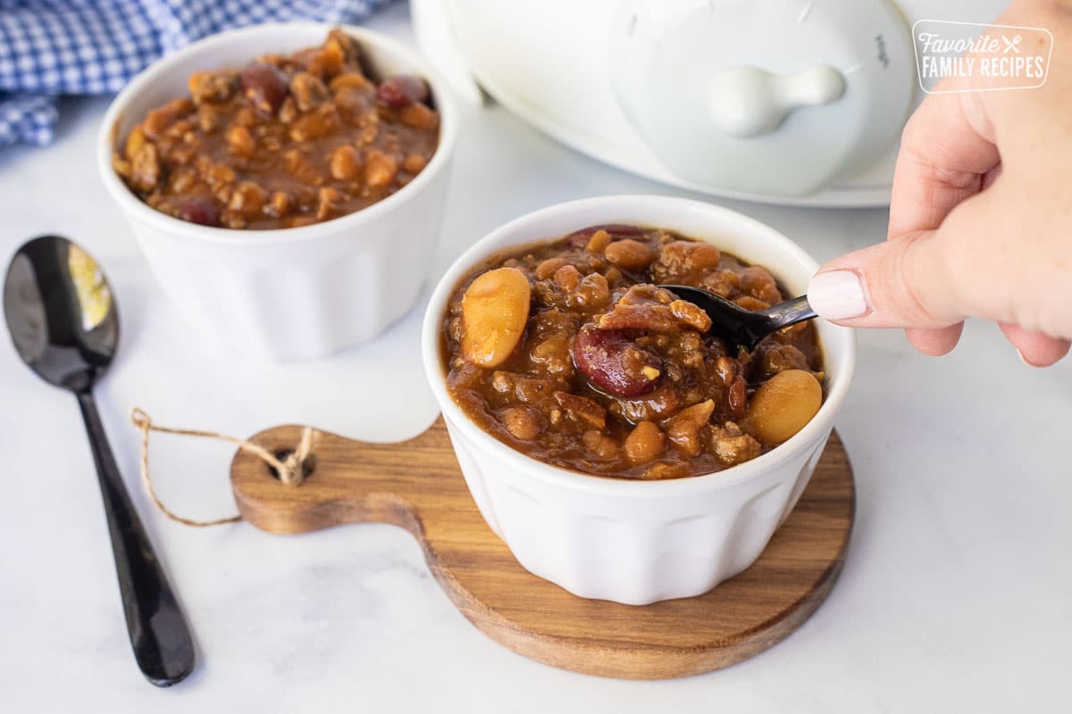Hand scooping a spoonful of Baked beans.