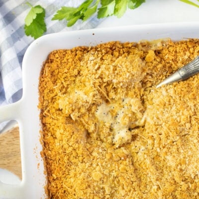 Spoon resting in a casserole dish of Poppy Seed Chicken.