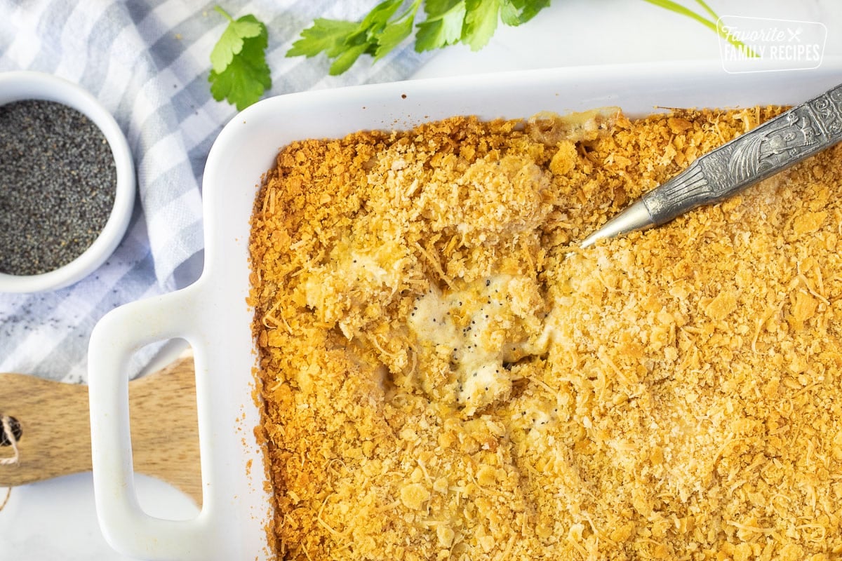 Spoon resting in a casserole dish of Poppy Seed Chicken.