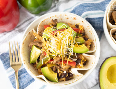 Steak Fajita Bowl in a flour tortilla topped with avocado and cheese.