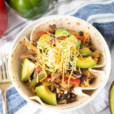 Steak Fajita Bowl in a flour tortilla topped with avocado and cheese.