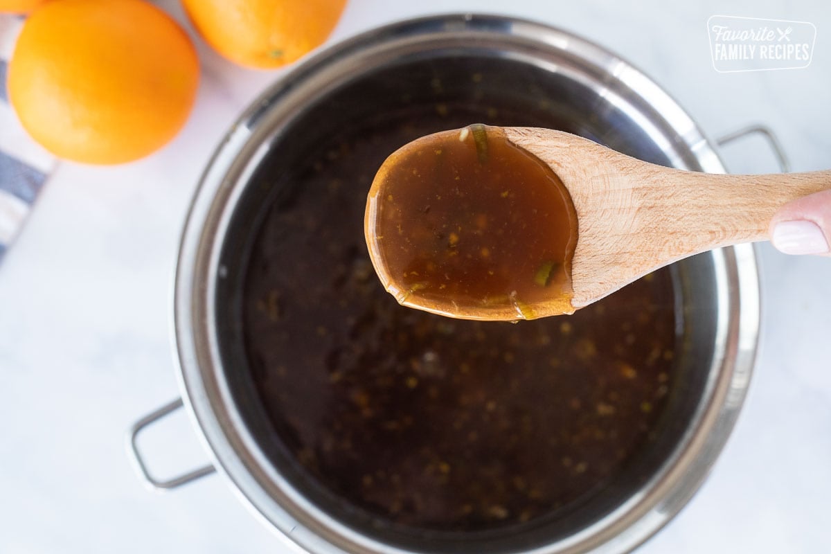 Spoon holding up thickened sauce for Orange Chicken.