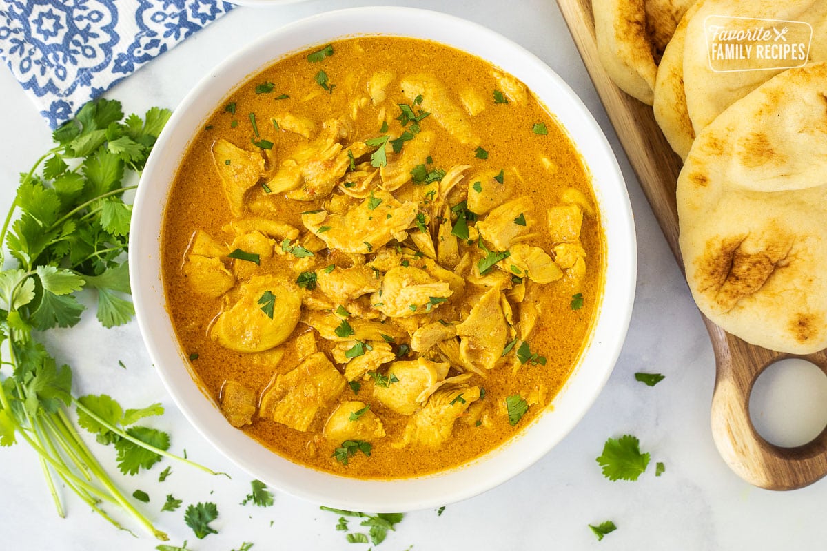 Large bowl of Chicken Korma with cilantro and naan bread.