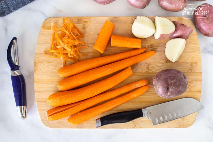 Cutting board with carrots and red potatoes for Crockpot Roast Beef.