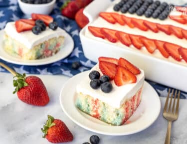 4th of July Cake with red and blue Jello topped with frosting, strawberries and blueberries.