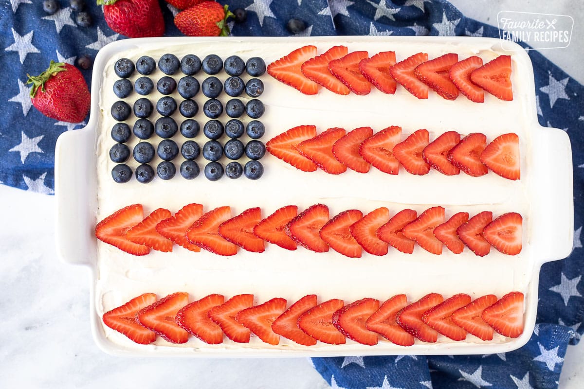 Baking dish with American Flag 4th of July Cake decorated with fresh sliced strawberries and blueberries.
