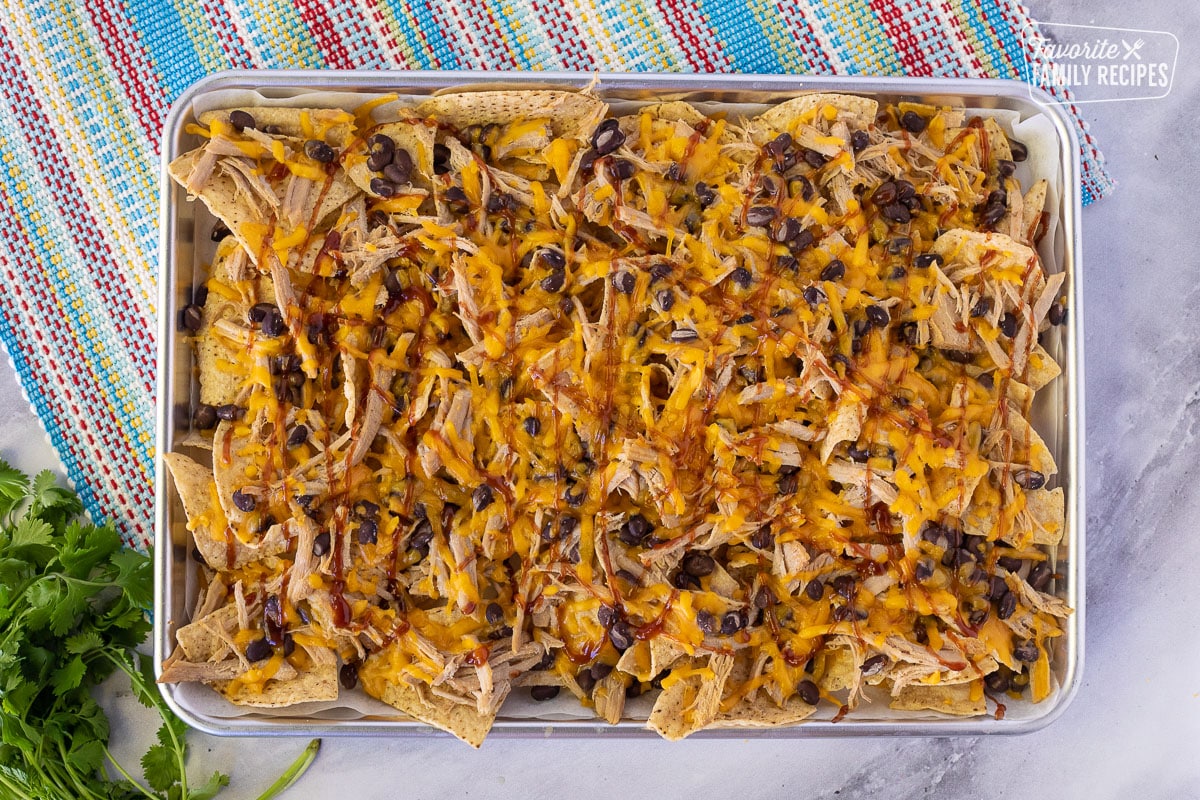 Baking sheet with Homemade BBQ sauce drizzled on top of Pulled Pork Nachos.