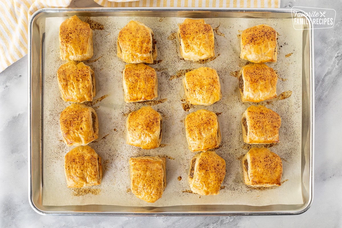 Sausage Rolls are a seasoned, fresh sausage wrapped in a flaky, buttery pastry. They are delicious for breakfast, lunch, or dinner, or as an appetizer. Sixteen baked Sausage Rolls on a baking sheet.