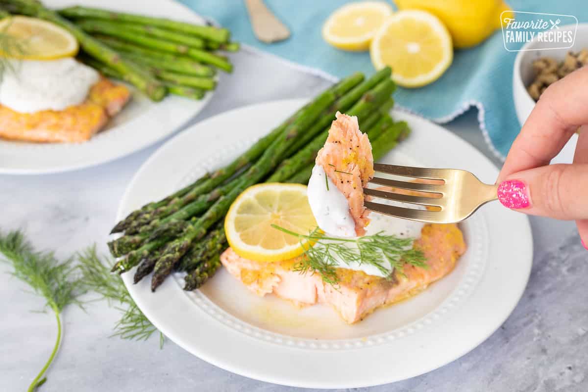 Fork holding a bite of Baked Lemon Salmon with Tzatziki sauce.