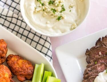 Blue Cheese Sauce next to a plate of steak and a plate of wings