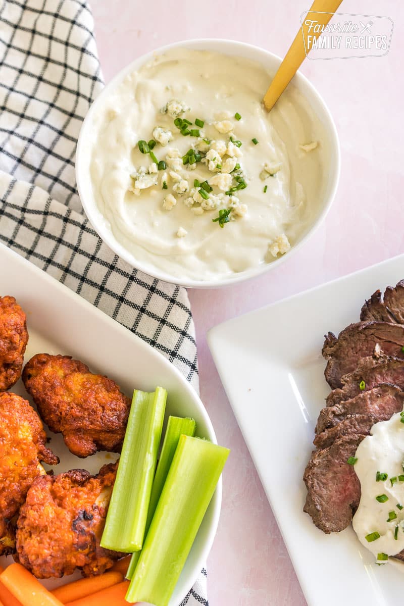 Blue Cheese Sauce next to a plate of steak and a plate of wings
