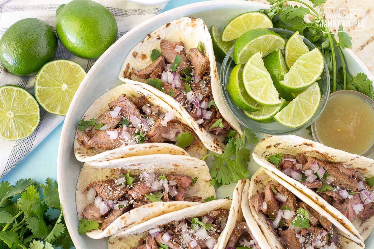 Close up of Street Tacos with limes, cilantro and red onions.