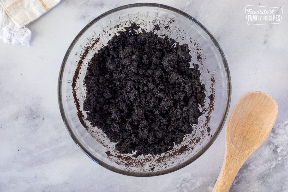Oreo and butter mixture in a glass bowl for Chocolate Satin Pie crust.