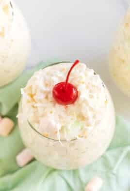 Frog eye salad in little cups topped with maraschino cherries