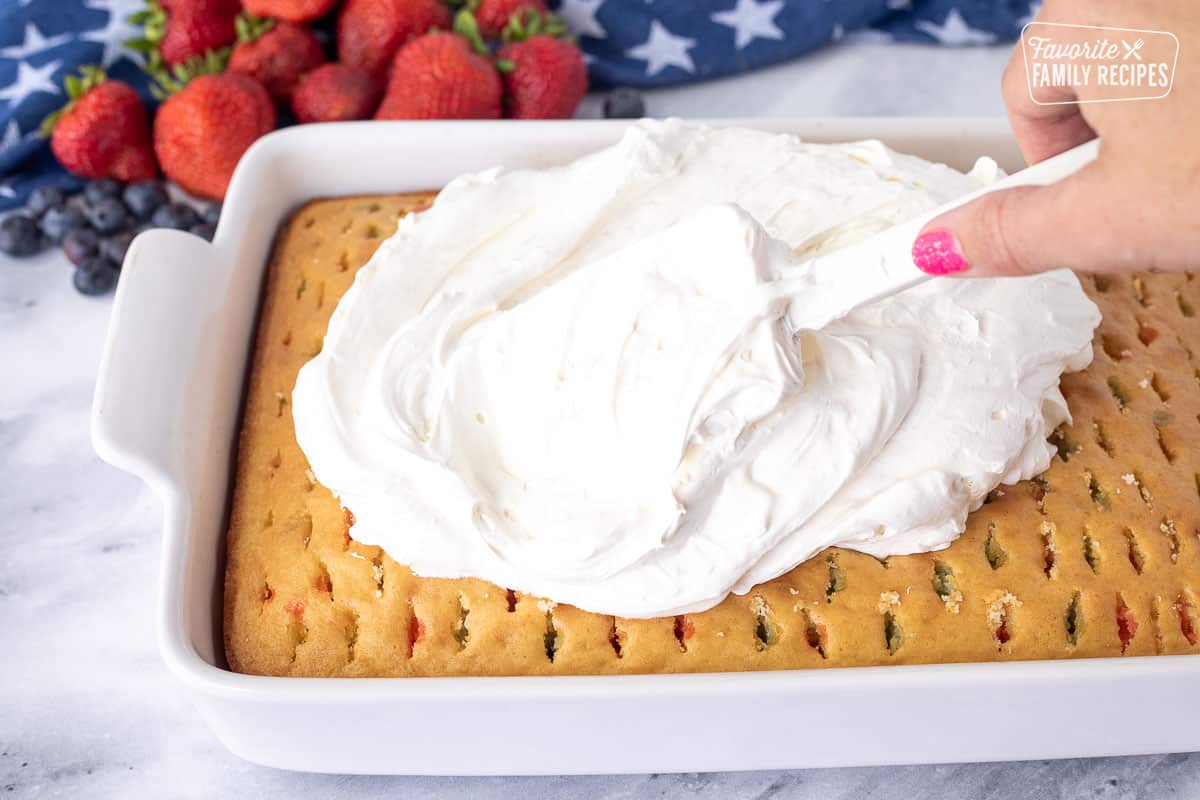 Frosting 4th of July Cake with a spatula.