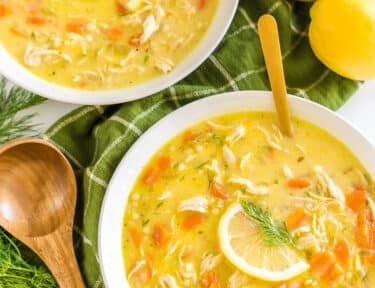 Two bowls of Greek Lemon Chicken Soup topped with lemon slices and fresh dill