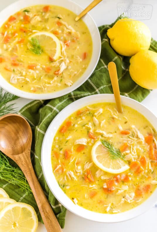 Two bowls of Greek Lemon Chicken Soup topped with lemon slices and fresh dill
