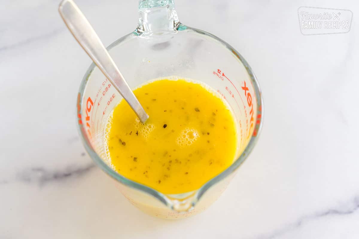 Tempered egg sauce in a glass measuring cup with a fork. 