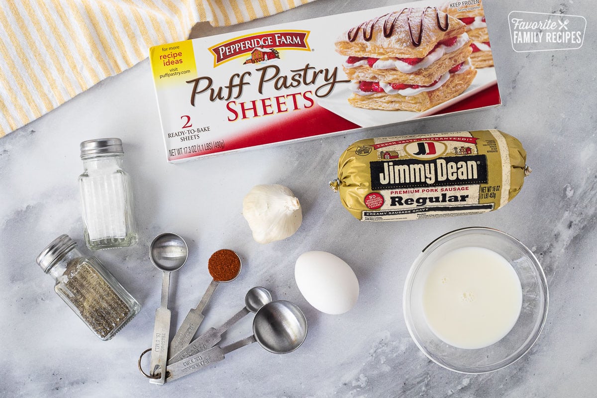 Ingredients to make Sausage Rolls including puff pastry, sausage, salt, pepper, paprika, egg, garlic, milk and bread crumbs.