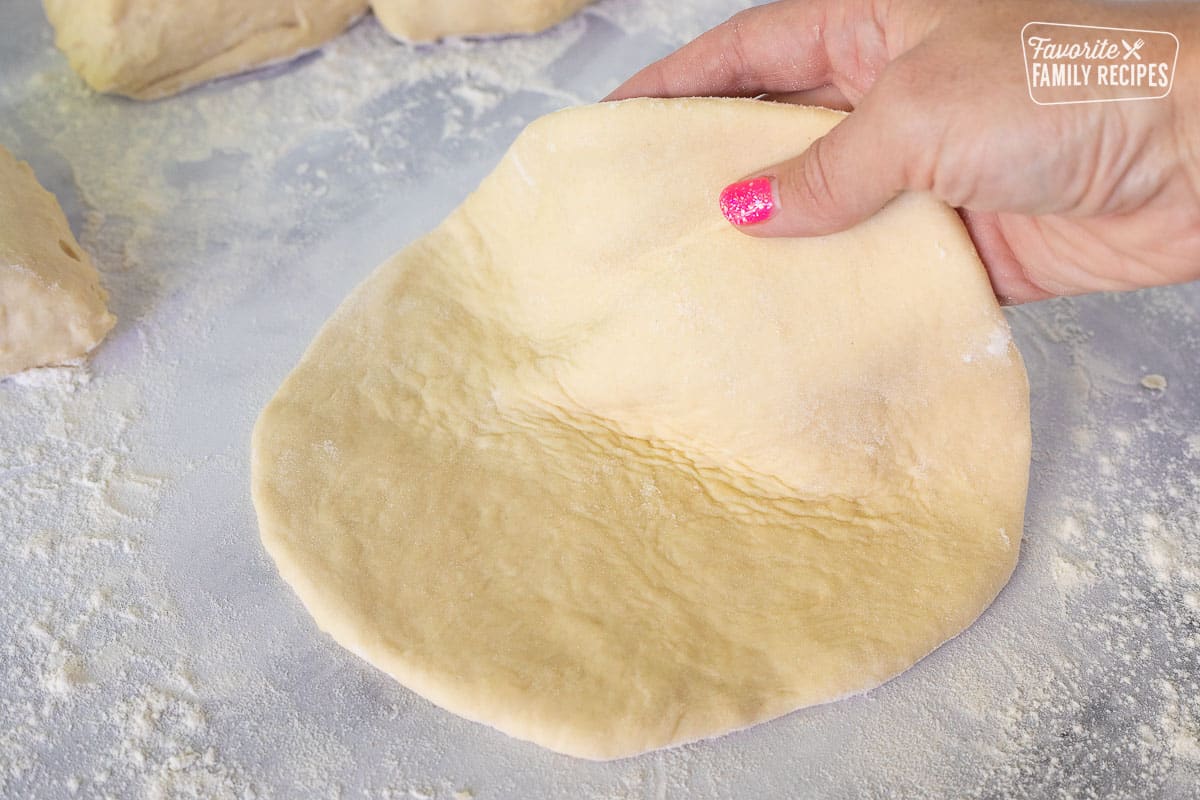 Lifting a flattened piece of dough for Fry Bread.