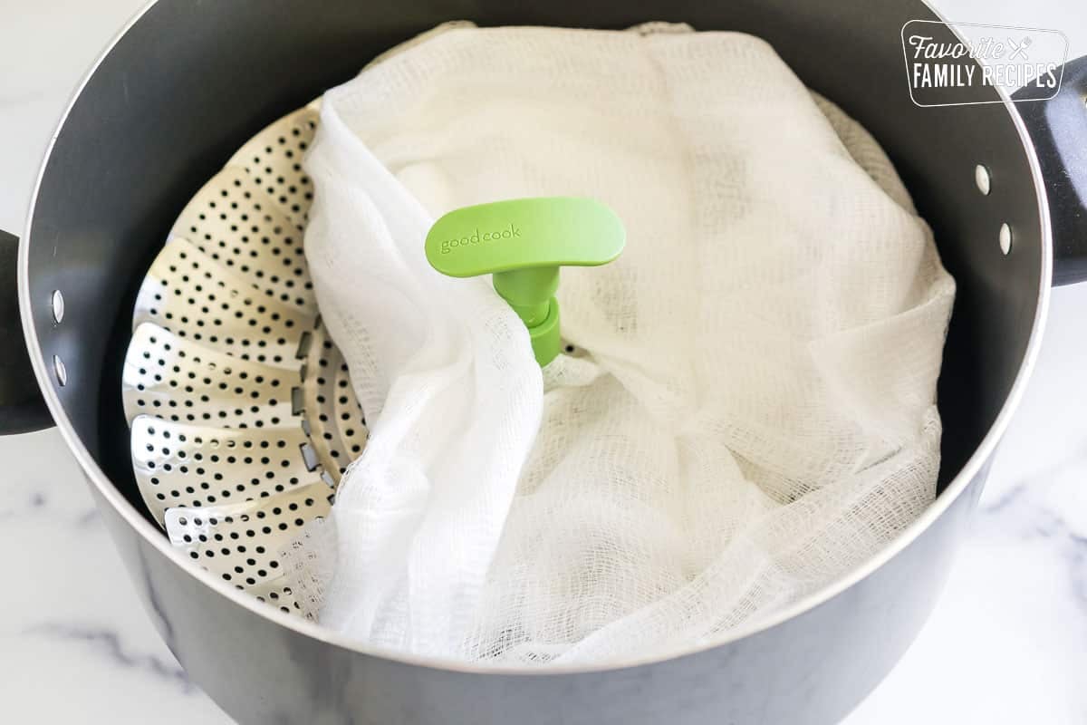 A steamer tray in a large pot covered with cheese cloth