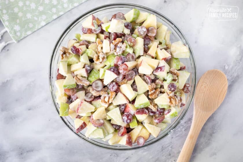 Bowl of mixed Waldorf Salad. Wooden spoon on the side.