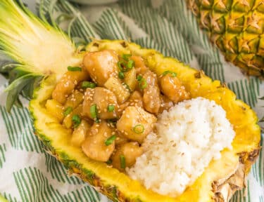 pineapple chicken and sticky rice served in a hollowed out pineapple half