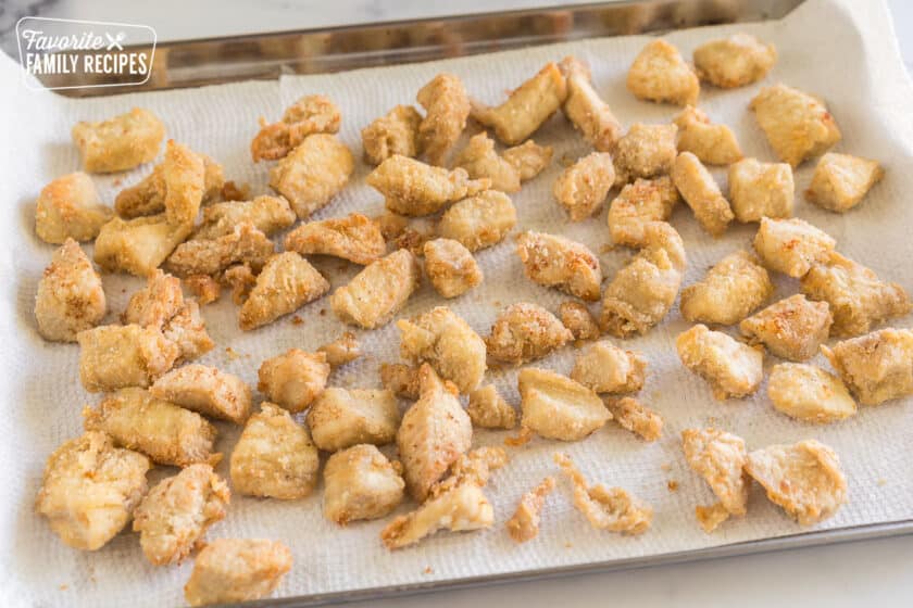 Lightly fried chicken pieces on a baking sheet