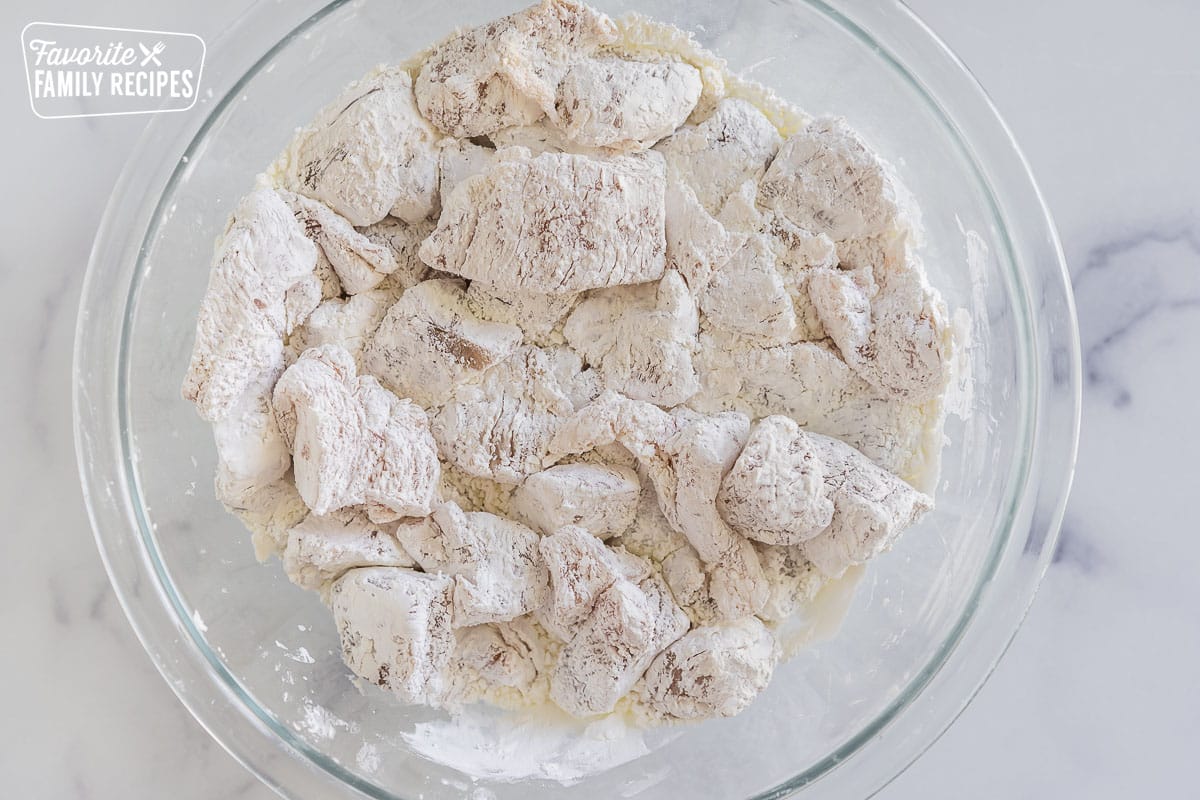 Chicken pieces coated in cornstarch in a bowl