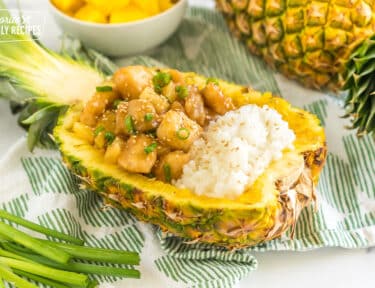 pineapple chicken and sticky rice served in a hollowed out pineapple half