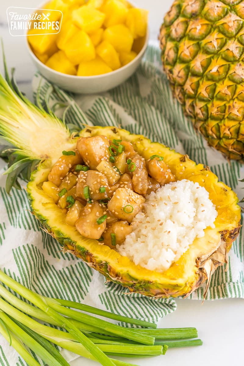 pineapple chicken and sticky rice served in a hollowed out pineapple half